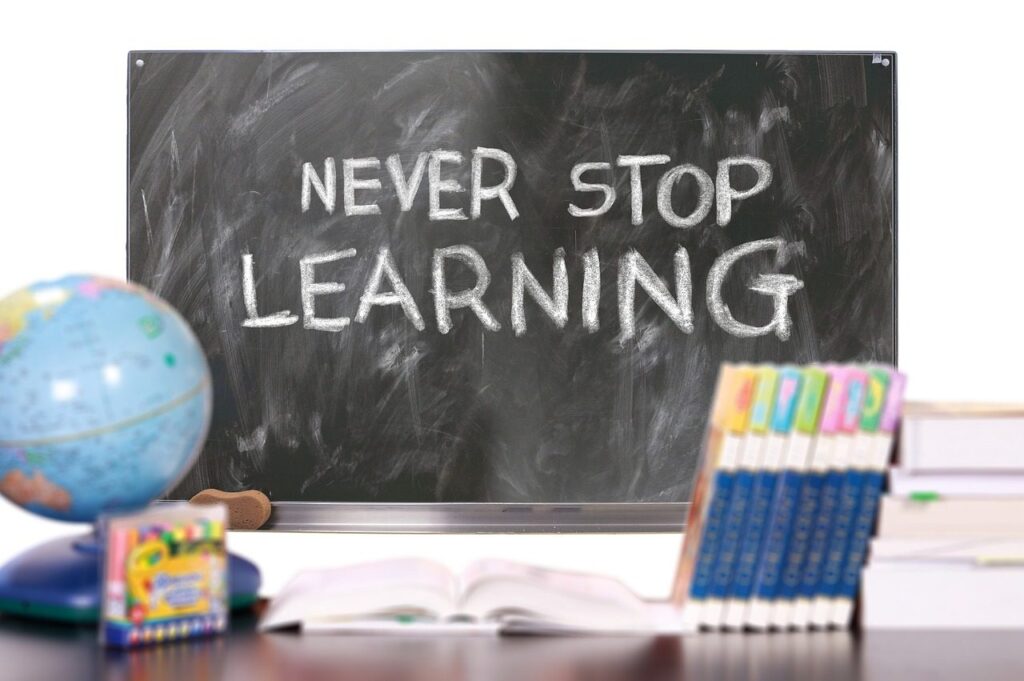 Crayons and coloured markers next to a chalkboard and a globe, for learning the colours in Italian